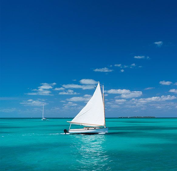 A boat with a white sail on turquoise sea
