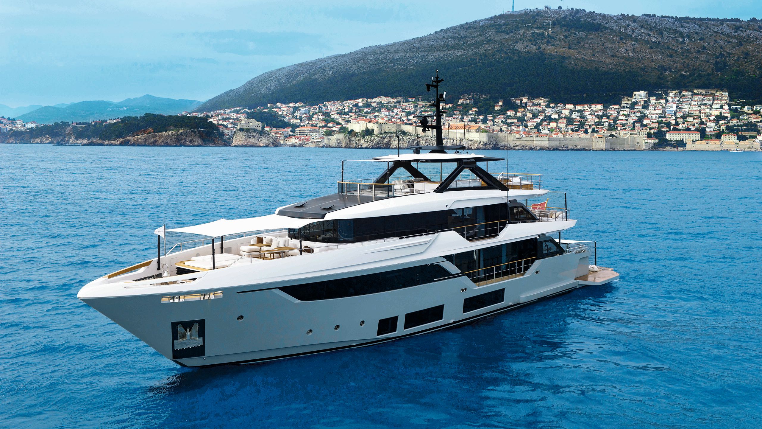 Exterior side view of Navatta 38 on the water, a coastal town is in the distance